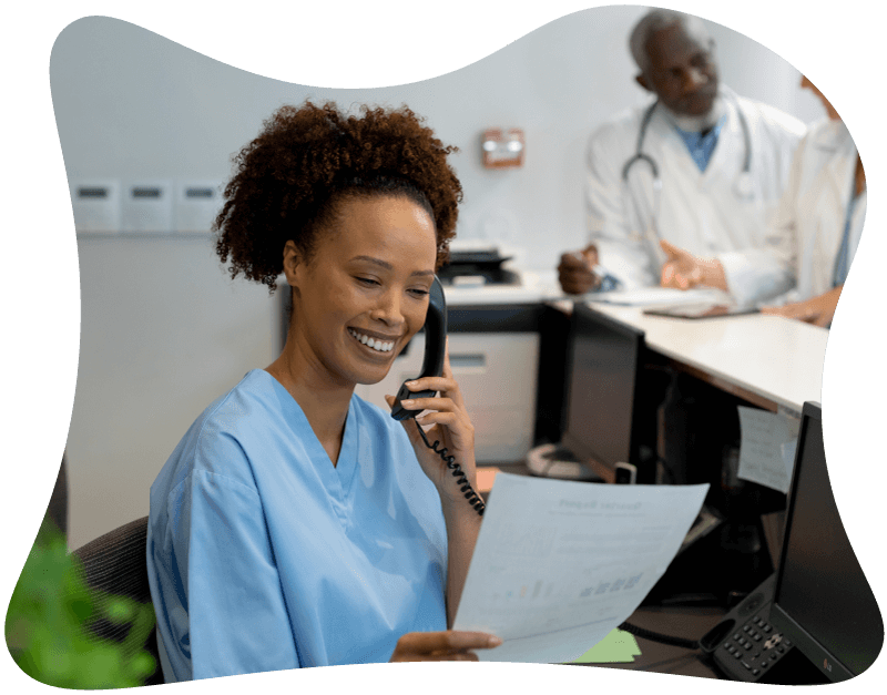Clinician managing the front desk, answering the phone and reviewing a scan form document.
